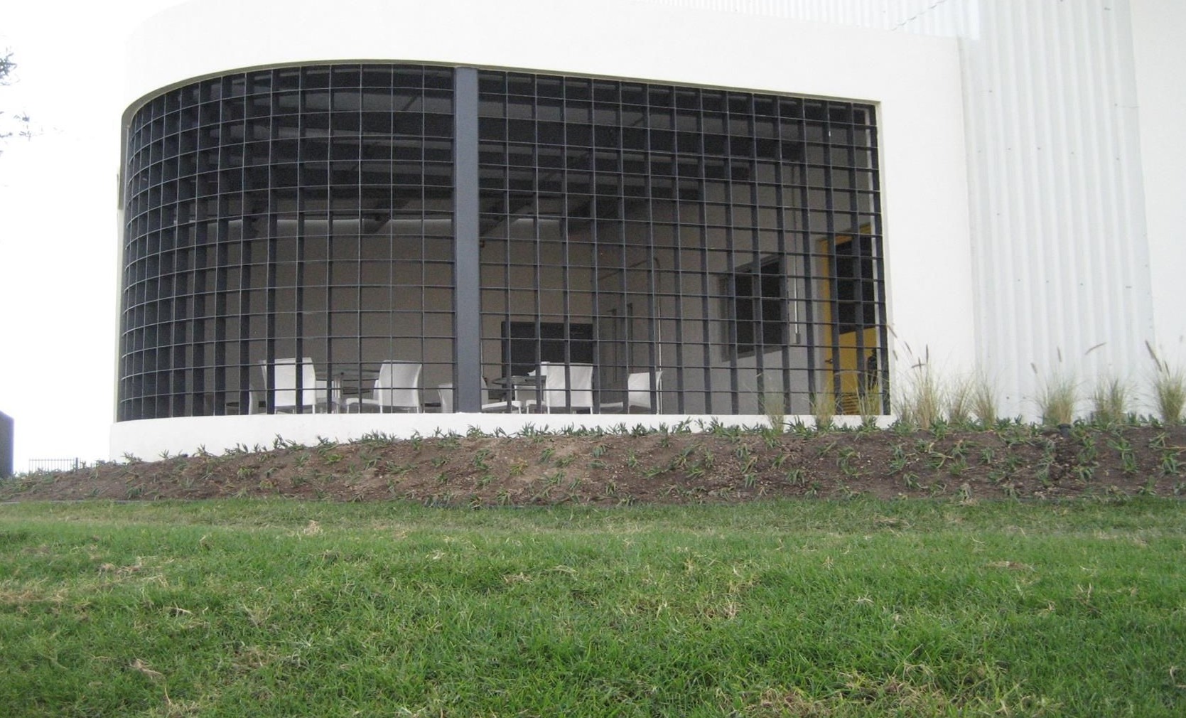 Fachada curva de reja metálica cuadrículada en proyecto comercial y residencial