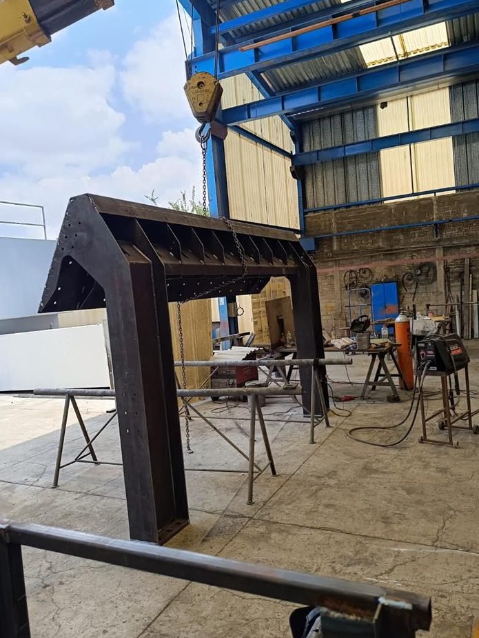 Estructura metálica en proceso de armado con grúa en taller